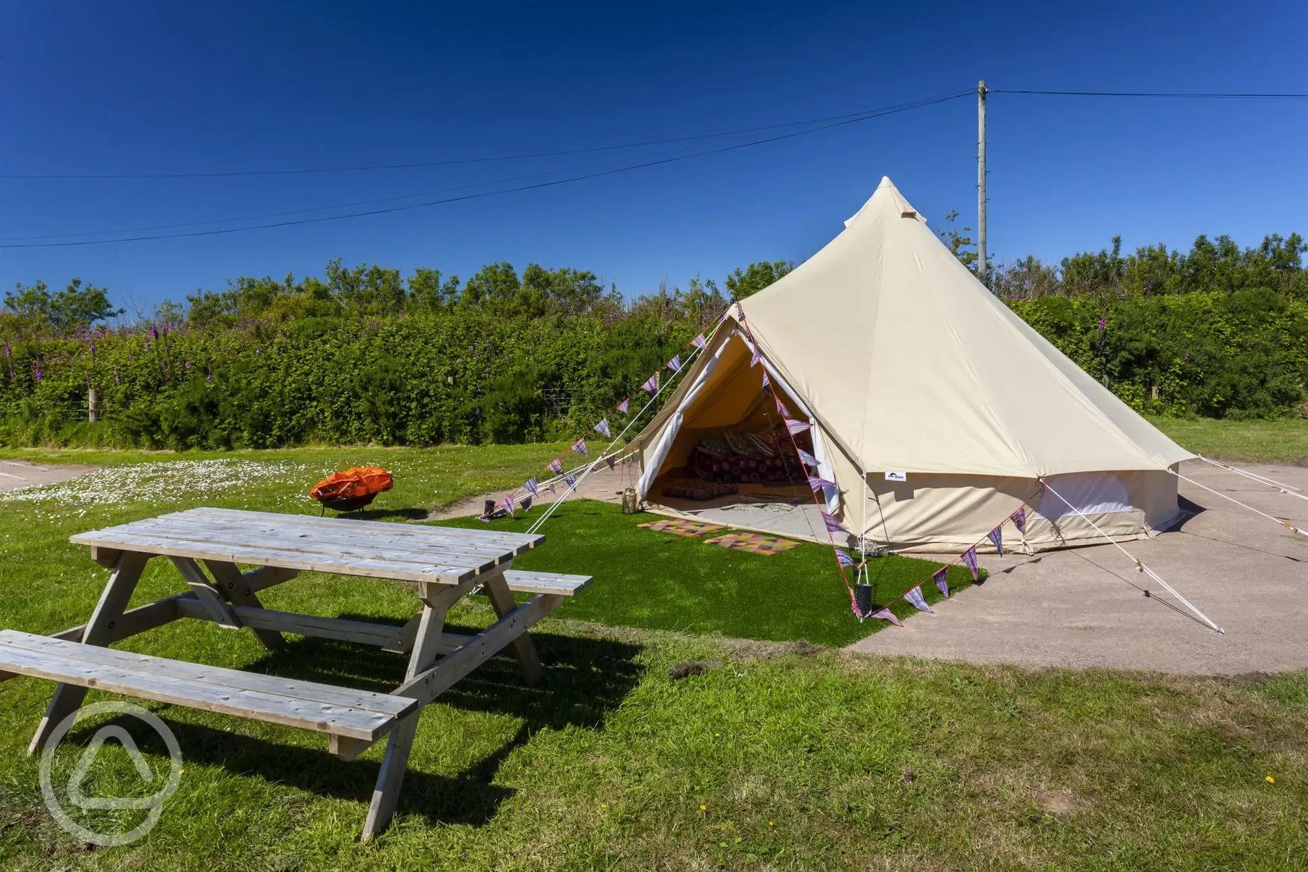 Bell tent exterior with picnic bench and solar lighting available