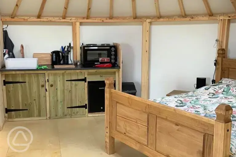 Roundhouse interior with a double bed and kitchenette
