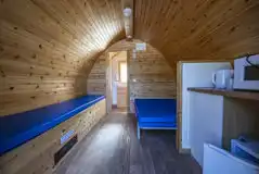Small ensuite hiker pod interior with double bed, bench and kitchen area