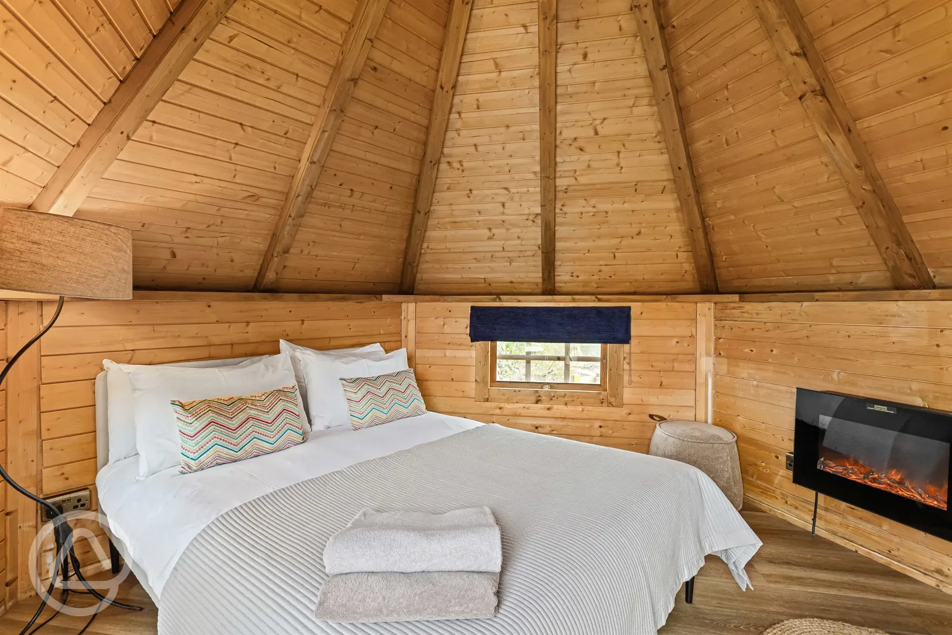 Chestnut glamping cabin interior with double bed and fireplace