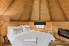 Chestnut glamping cabin interior with double bed and fireplace