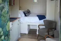 Honey shepherd's hut interior with double bed, seating and kitchenette