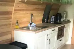 Luxury Cedar Pod fully equipped kitchenette with a sink, kettle, and oven