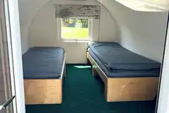 Camping pod interior with two single bench beds and a single camp mattress