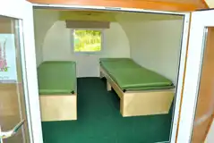Camping pod interior with two single bench beds and a single camp mattress