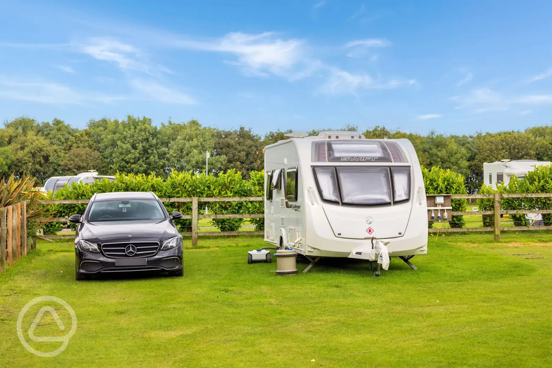 Electric grass pitches (Family Area) with a parked car beside the pitch