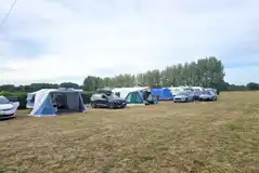 Large tents on electric grass tent pitches with space for a parked car