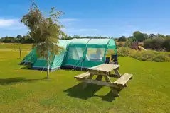 Grass pitches with picnic benches dotted around the campsite