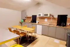 Bunkhouse shared kitchen with appliances, a dining table, and TV