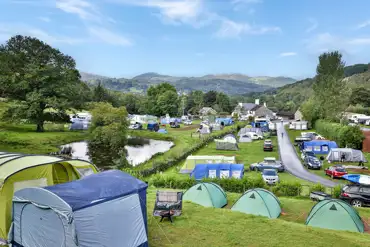 Site overview with grass and hardstanding pitches and a pond view