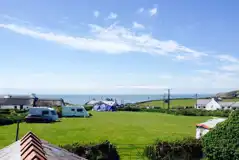 Overview of the camping field with grass pitches and views towards the coast