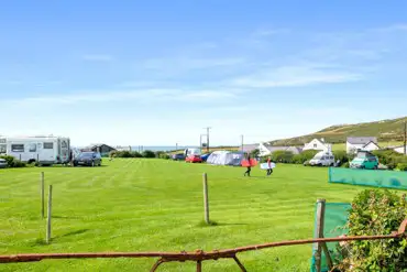 Overview of the camping field with grass pitches and views towards the coast