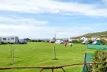 Overview of the camping field with grass pitches and views towards the coast