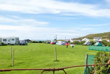 Overview of the camping field with grass pitches and views towards the coast