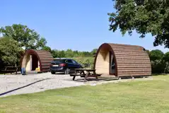 Camping pod exterior with space for a car and outdoor seating