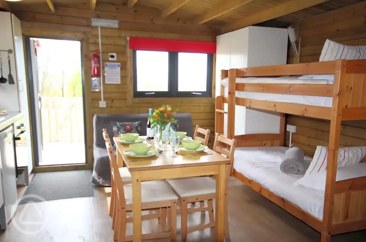 Glamping cabin with a double bed, bunk beds, dining area and kitchen