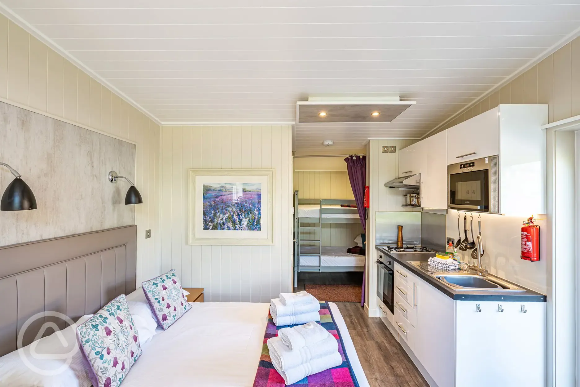 Merlin's Cabin interior with a double bed and bunk beds (bedding provided)