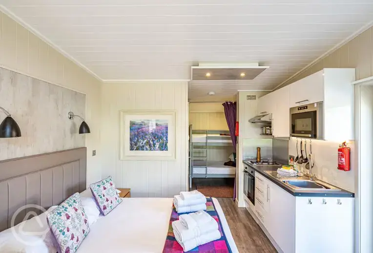 Merlin's Cabin interior with a double bed and bunk beds (bedding provided)