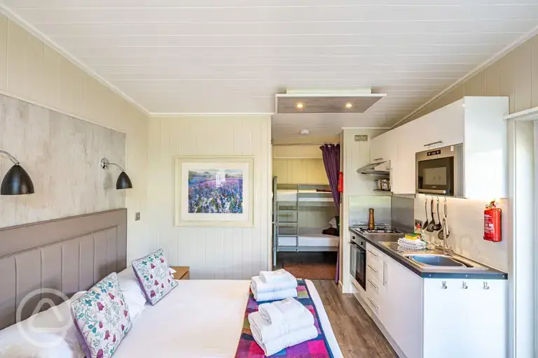 Merlin's Cabin interior with a double bed and bunk beds (bedding provided)
