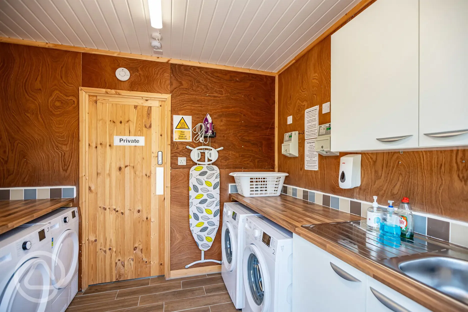 Laundry room with coin-operated washing machines, dryers, and ironing facilities