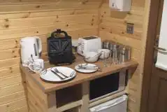 Log pod kitchenette with a kettle, microwave, toaster and fridge