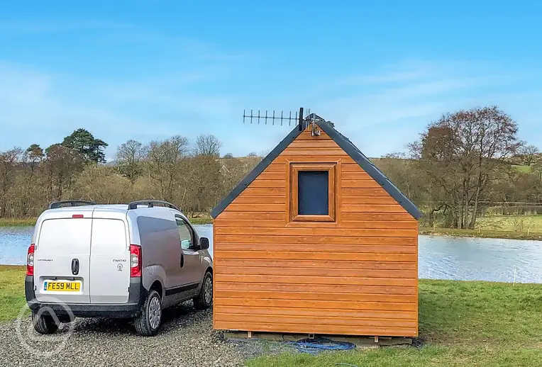 Log pod exterior overlooking the lake with a double bed inside