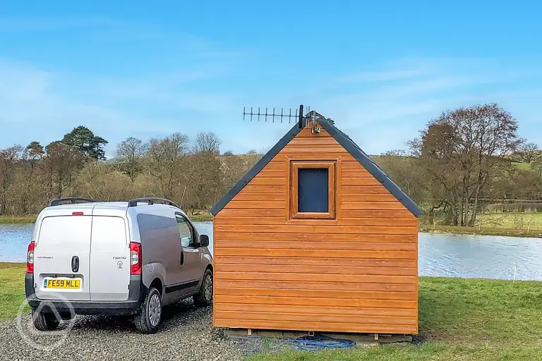 Log pod exterior overlooking the lake with a double bed inside
