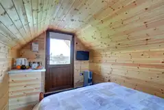 Log pod interior with tv, kitchenette and an electric heater.
