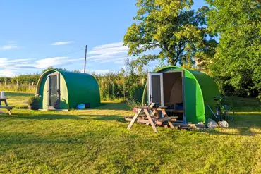 Green camping pods with picnic benches