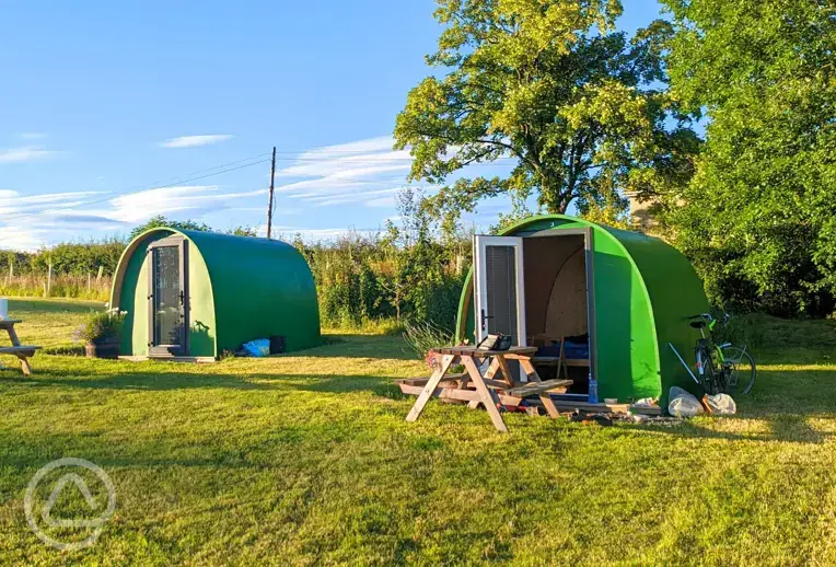Green camping pods with picnic benches