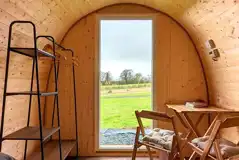 Green camping pod interior with a double bed, table, chairs and storage