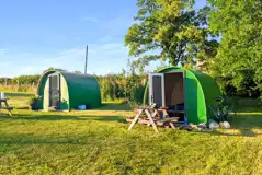Green camping pods with picnic benches