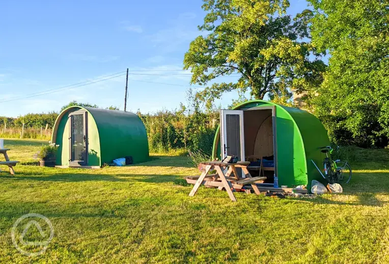 Green camping pods with picnic benches