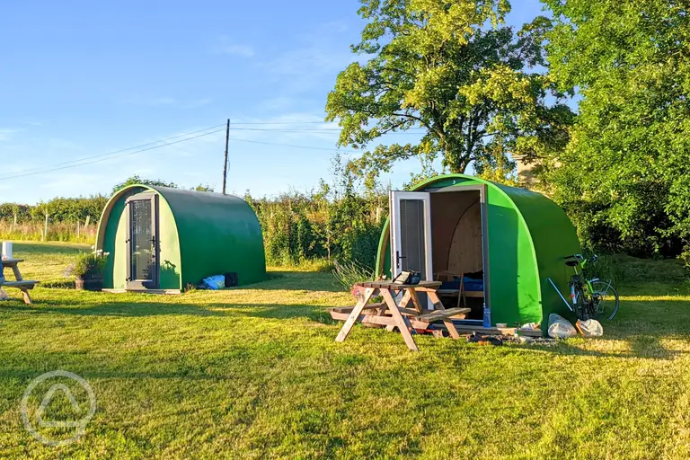 Green camping pods with picnic benches