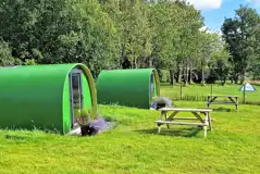 Green camping pods with picnic benches