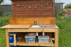 Goldfinch bell tent's outdoor kitchen with cooking equipment, a sink, and more Goldfinch bell tent's outdoor kitchen with cooking equipment, a sink, and more