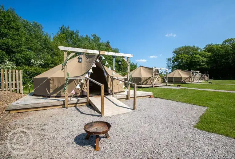 Bell tents with a double bed, futon bed, stove, and fire pit