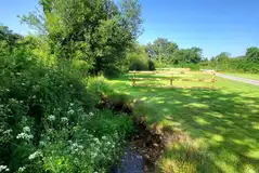 Electric grass pitches with fences beside a stream
