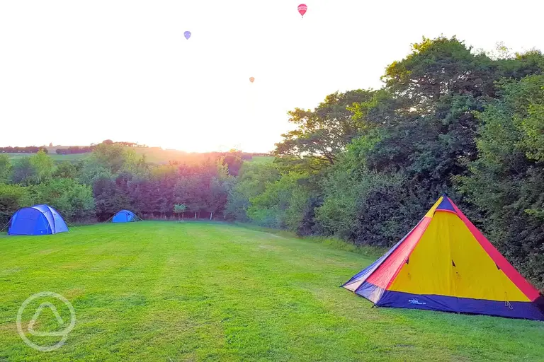 Boyd Valley Lake non electric grass pitches with hot air balloons in the sky