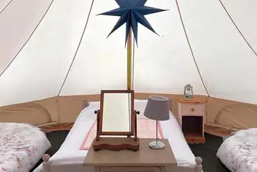 Bell tent interior with a double bed and two singles