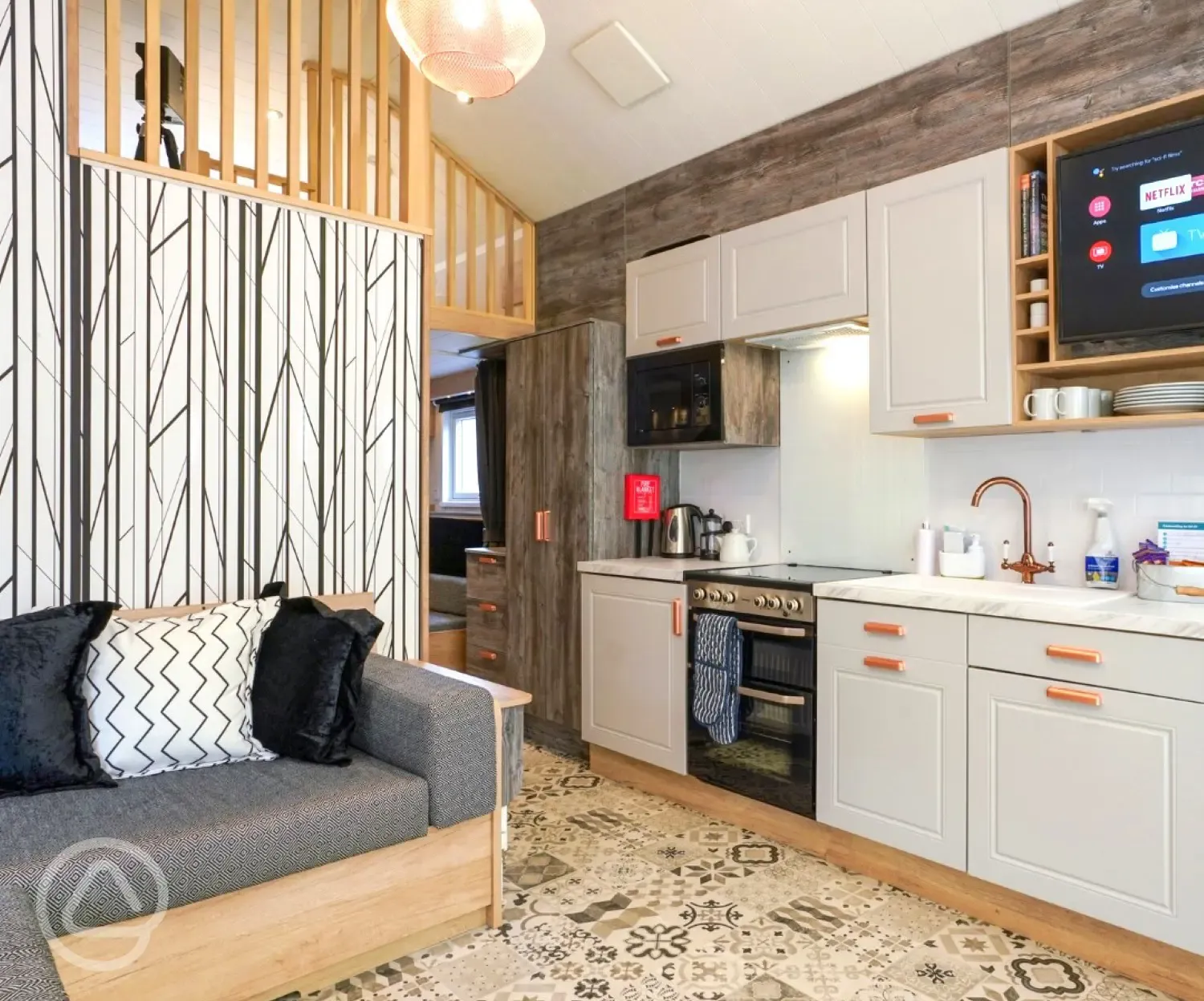 Ensuite glamping cabin interior with a sofa bed, kitchen and mezzanine level