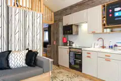 Ensuite glamping cabin interior with a sofa bed, kitchen and mezzanine level Ensuite glamping cabin interior with a sofa bed, kitchen and mezzanine level