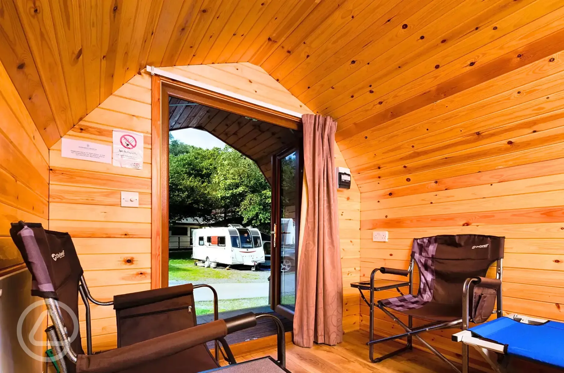 Camping pod interior with two single camp beds, camp chairs and electric sockets