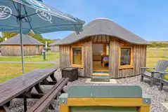 Wooden yurt with outdoor seating and a parasol