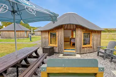 Wooden yurt with outdoor seating and a parasol