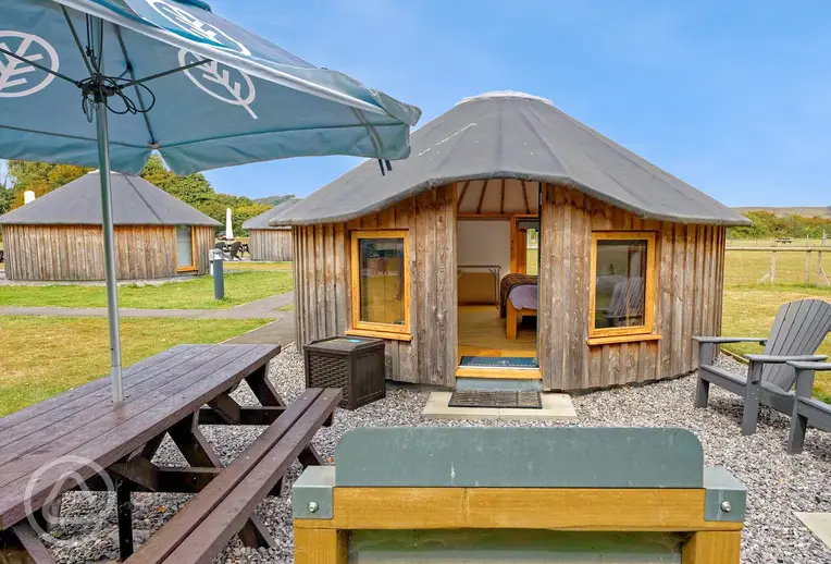 Wooden yurt with outdoor seating and a parasol