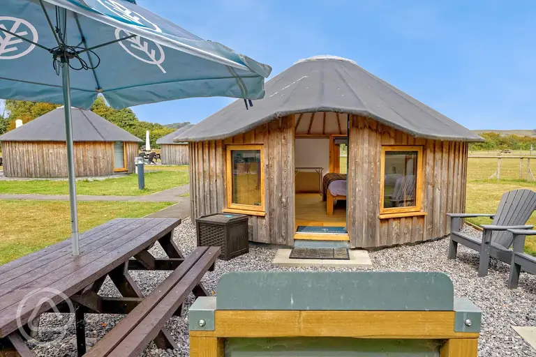 Wooden yurt with outdoor seating and a parasol