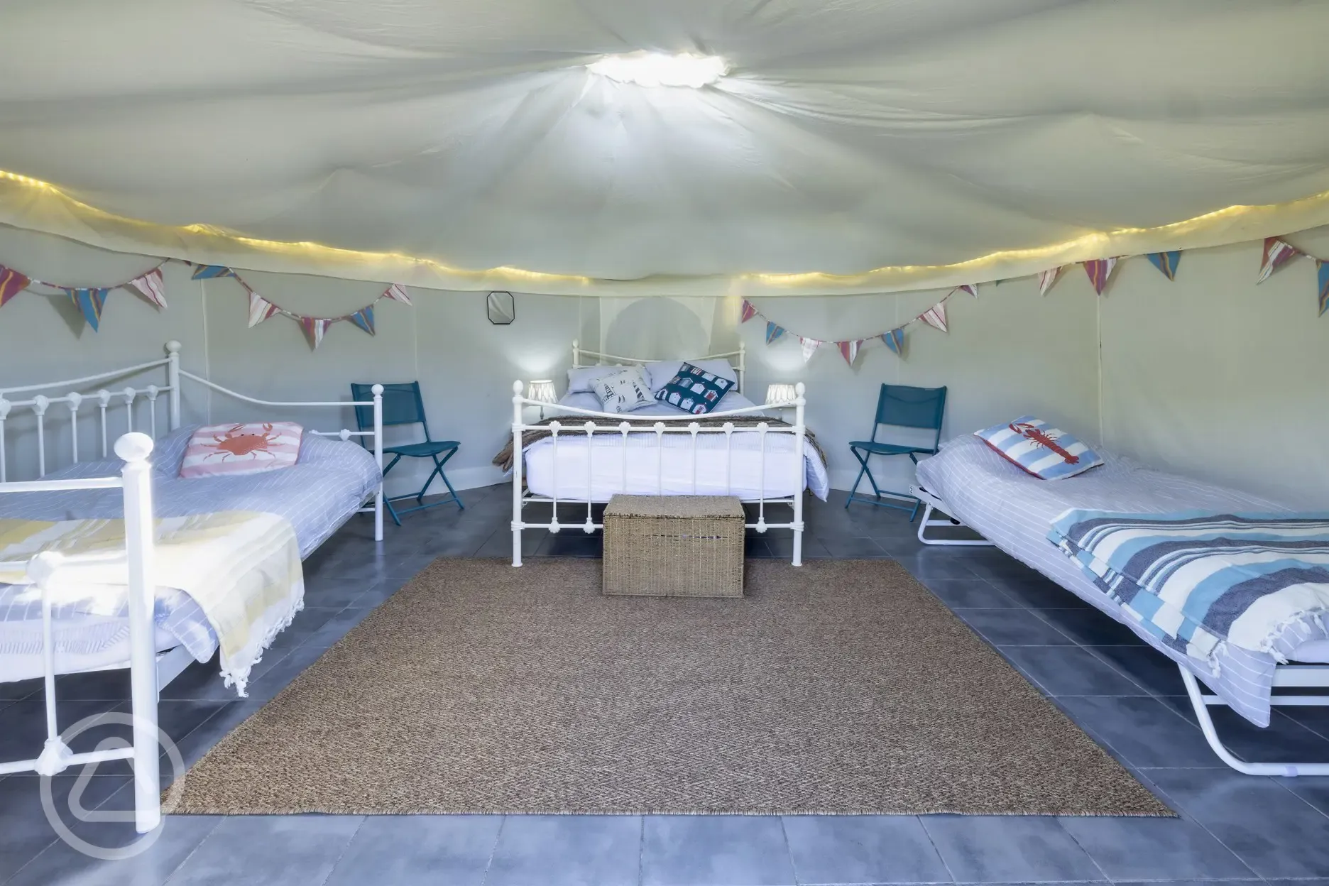 Yurt interior with a double bed and two singles (bedding provided)