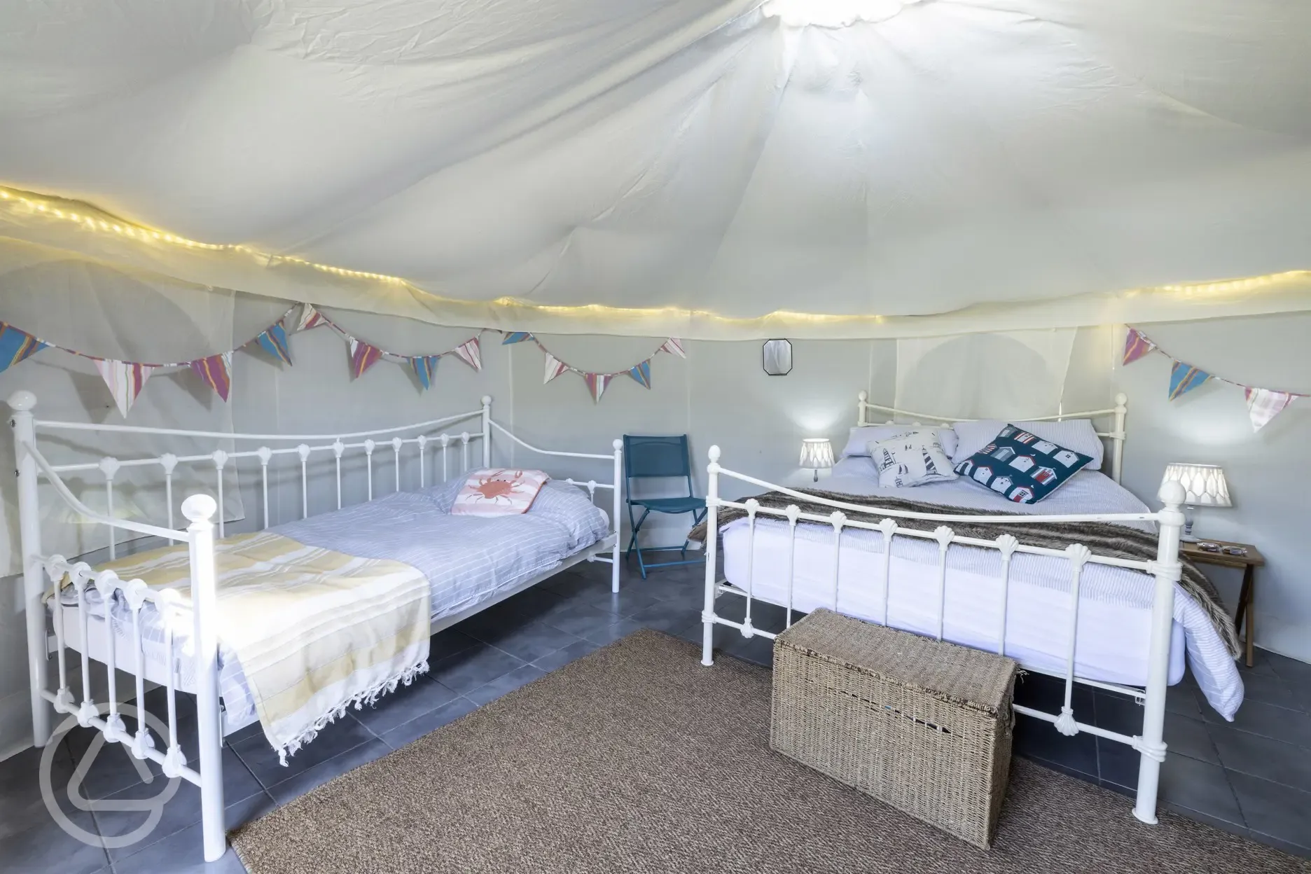 Yurt interior with a double bed and two singles (bedding provided)