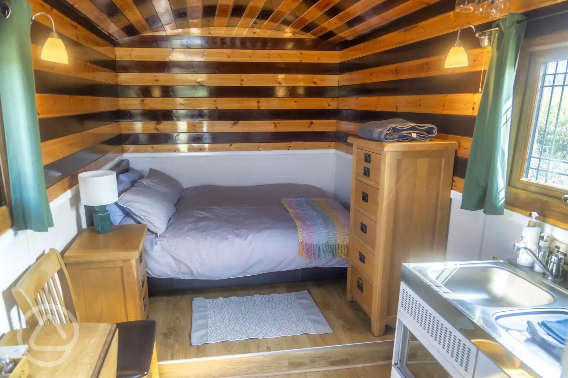 Shepherd's hut interior with a double bed, storage units, and a kitchenette